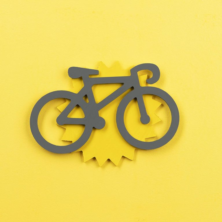 Une personne souriante fait du vélo sur une piste cyclable ensoleillée.